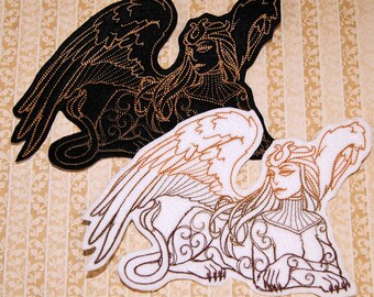 May include: Two embroidered patches featuring a sphinx design. One patch is black with gold-colored detailing, and the other is white with gold-colored detailing. The sphinxes are depicted in a reclining pose with wings and intricate patterns.