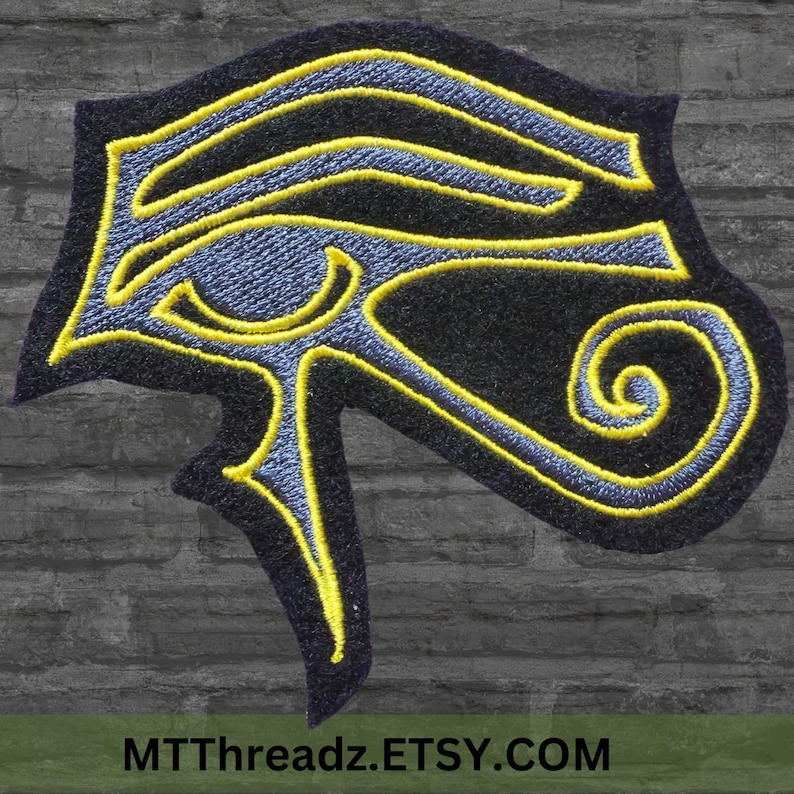 Puede incluir: Un parche bordado con el Ojo de Horus, un s&iacute;mbolo de protecci&oacute;n y poder en la mitolog&iacute;a egipcia antigua. El parche es negro con bordados amarillos y azules.