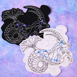 May include: Two embroidered patches depicting the constellation Capricorn. One patch is black with white stitching, the other is white with black stitching. Both patches feature a stylized sea-goat with a constellation of stars.