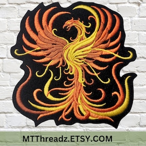 May include: Embroidered iron-on patch featuring a stylized phoenix with orange and yellow flames against a black background. The patch is approximately 5 inches wide and 6 inches tall.