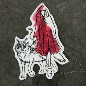 May include: Embroidered patch featuring a girl in a red hooded cloak walking with a wolf. The girl is wearing a red dress and black boots. The wolf is black and white.