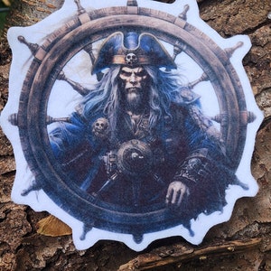 May include: A white circular patch with a blue and white pirate holding a steering wheel. The pirate has a long white beard and is wearing a blue and white hat with a skull and crossbones on it. The steering wheel is made of wood and has a rope wrapped around it.