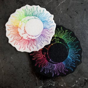 May include: Two embroidered patches with a rainbow sun and moon design. One patch is white with a white background and the other is black with a black background.
