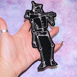 May include: White embroidered iron man with an axe on a black felt patch.