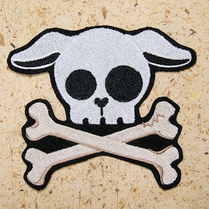 May include: White skull with bunny ears and crossed bones, embroidered patch.