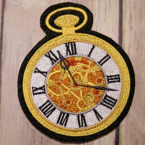 May include: A gold-colored pocket watch with Roman numeral markings on the face. The watch has a black rim and a black chain attached to the top.