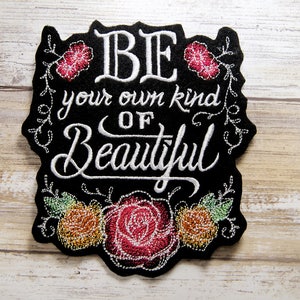 May include: Black embroidered patch with white lettering that reads "BE your own kind of Beautiful" surrounded by embroidered flowers.