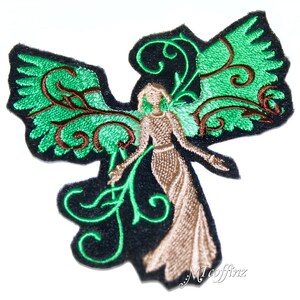 May include: Green and brown embroidered patch of an angel with wings and a floral design. The angel is wearing a long, flowing dress.