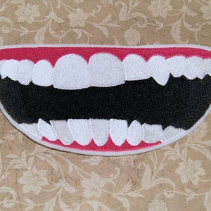 May include: A white felt patch with a red outline depicting a large, open mouth with white teeth. The mouth is wide open, showing a black interior.
