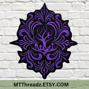 May include: Purple embroidered patch with a black background featuring a stylized tree with a bird perched on a branch, surrounded by a cemetery with crosses. The design is framed by a decorative floral pattern.