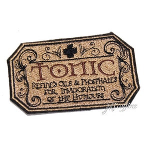 May include: A brown and black embroidered patch with the text "Tonic" in brown lettering. The text "Remedies Oils & Phosphates for Invigoration of the Humours" is also embroidered in brown lettering.