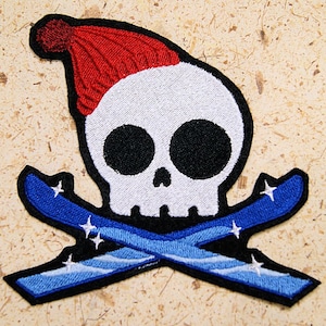 May include: Embroidered patch featuring a white skull wearing a red knit hat, with crossed blue ski poles. The ski poles have white stars on them.
