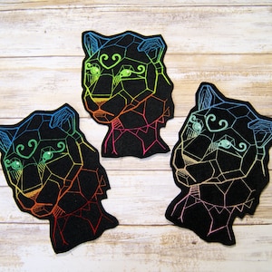 May include: Three black felt patches with geometric designs of a panther's head. Each patch has a different rainbow color scheme.