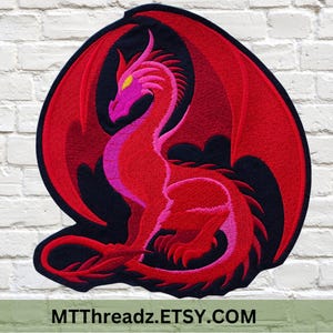 May include: Embroidered patch featuring a red dragon with large wings, a long tail, and a detailed design. The dragon has a pink head and body, with yellow eyes, set against a black background. The text "MTThreadz.ETSY.COM" is at the bottom.