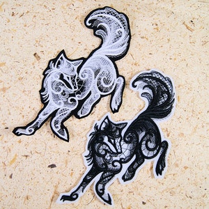 May include: Two embroidered iron-on patches of wolves in a stylized, lacy design. One wolf is white and the other is black.