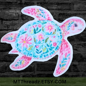 May include: A die-cut sticker featuring a sea turtle with a watercolor-style shell and flippers decorated in pink, blue, and yellow floral patterns. The turtle has a light pink head with a visible eye. The text MTTREADZ.ETSY.COM is at the bottom.
