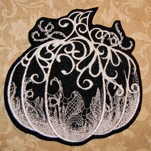May include: Black felt pumpkin patch applique with white embroidery. The pumpkin is outlined in white and has a white vine design.