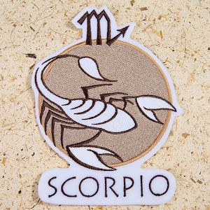 May include: Embroidered brown and white patch with a scorpion design and the word "SCORPIO" in white lettering.