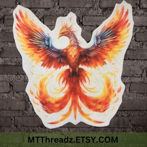 May include: A colorful embroidered patch featuring a phoenix with orange, yellow, and blue feathers. The phoenix is depicted with its wings spread wide and its tail feathers flowing behind it. The patch is on a white background.