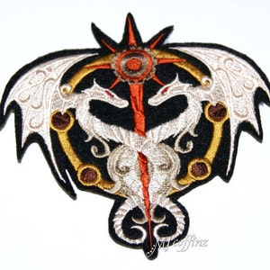 May include: Embroidered patch featuring two white dragons facing each other, intertwined around a central sunburst design with a red and orange color scheme. The dragons have gold accents and are set against a black background.
