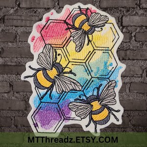 May include: Embroidered patch featuring three bees with black and yellow stripes, flying around a honeycomb with a rainbow watercolor effect. The text "MTTThreadz.ETSY.COM" is at the bottom of the patch.