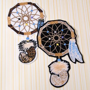 May include: Two embroidered dreamcatcher patches with brown, white and blue details. The dreamcatchers have a circular design with a web-like pattern and feathers hanging from the bottom.