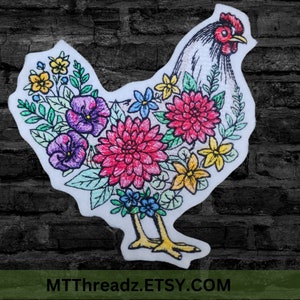May include: White embroidered chicken with a floral design. The chicken is surrounded by colorful flowers, including pink, purple, yellow, and blue. The design is on a white background.