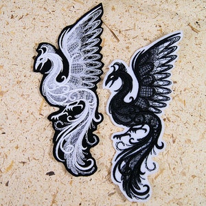 May include: Two embroidered iron-on patches of phoenixes, one white and one black, with intricate details and a lace-like design.