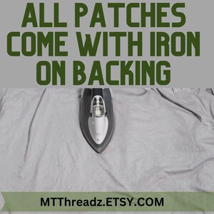 K&ouml;nnte beinhalten: Ein graues B&uuml;geleisen mit einem wei&szlig;en Griff liegt auf einer grauen Stoffoberfl&auml;che. Der Text "ALL PATCHES COME WITH IRON ON BACKING" befindet sich oben im Bild. Der Text "MTTThreadz.ETSY.COM" befindet sich unten im Bild.
