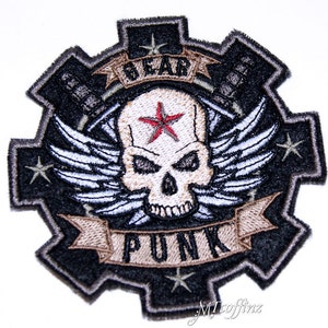 Peut inclure: Patch brodé noir et beige avec un crâne ailé et une bannière qui dit "Gear Punk".