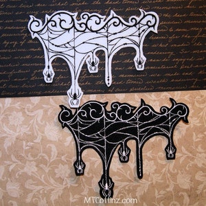May include: Two black and white embroidered patches featuring a spider web design with dangling spiders. The patches are on a brown background with a floral pattern.