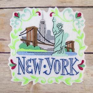May include: Embroidered patch with a white background and a green, blue, and brown image of the Statue of Liberty, the Brooklyn Bridge, and the New York City skyline. The text "NEW YORK" is written in blue with white stitching.