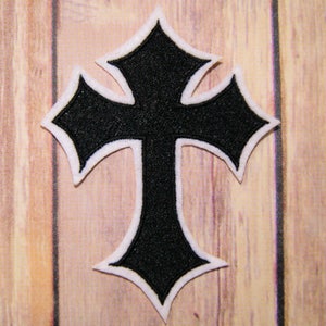 May include: Black iron cross patch with a white outline. The cross has a pointed design and is embroidered with a textured fabric.