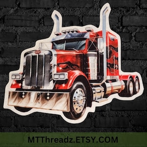 May include: A red, white, and black semi-truck with flames painted on the side. The truck has a large grill and chrome accents. The truck is on a white background.