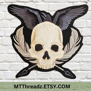May include: Black embroidered patch with a white skull, two crossed quill pens, and two black birds with wings spread out.