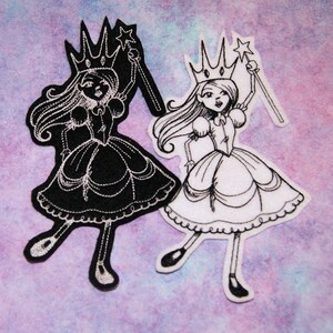 May include: Two embroidered iron-on patches of a princess with a crown and wand. One patch is black with white embroidery and the other is white with black embroidery.