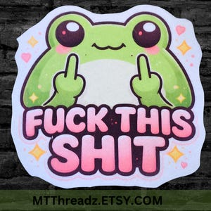 May include: A sticker featuring a cartoon frog with a light green body, pink cheeks, and large dark eyes. The frog is giving the middle finger with both hands. The words "FUCK THIS SHIT" are in pink and white text.