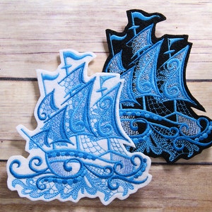 May include: Two embroidered patches of a blue ship with white and black outlines. The ship is on a white background with a blue wave design. The patches are on a wooden surface.