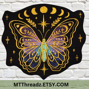 May include: Embroidered black patch featuring a butterfly with intricate gold, purple, and blue details. The design includes crescent moons, stars, and the text MTThreadz.ETSY.COM. The patch has a unique shape.