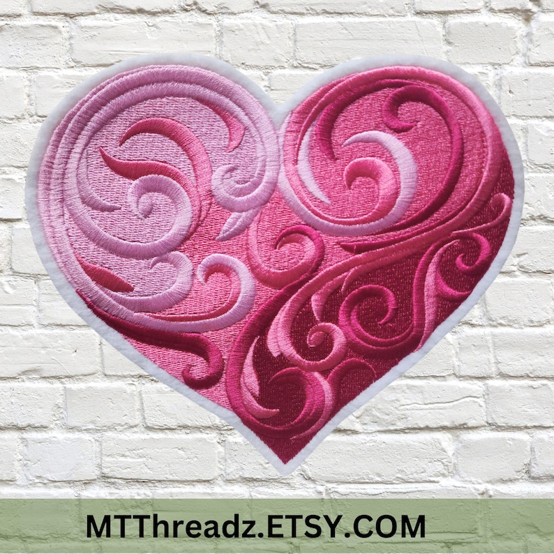 May include: A pink and red embroidered heart with a white outline and intricate swirling designs. The heart is on a white brick background.