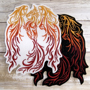 Peut inclure: Deux patchs brodés thermocollants représentant un phénix stylisé en rouge, orange et jaune. Un patch est sur fond blanc, l'autre sur fond noir.