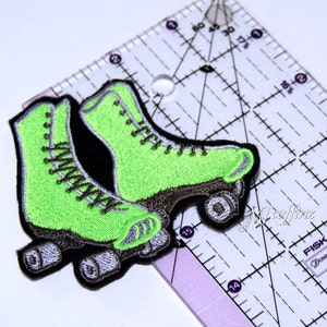 May include: A pair of green roller skates with black wheels and silver accents. The skates are embroidered and have a vintage style.