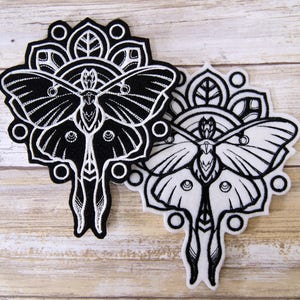May include: Two black and white embroidered iron-on patches featuring a moth with a mandala design. The moth is in a black and white color scheme.