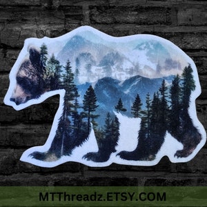 May include: A black bear silhouette with a mountain range and forest scene inside. The bear is facing left and the mountain scene is a blue and white watercolor style.