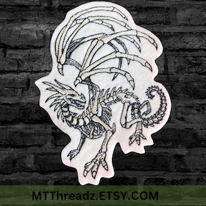 May include: Embroidered patch of a skeletal dragon with outstretched wings. The dragon is in a light beige colour with black stitching. The patch is on a white background.