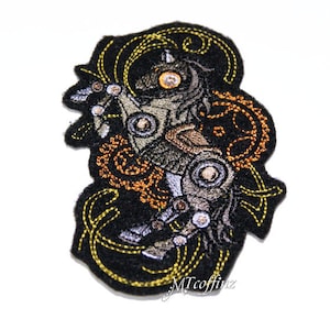 May include: Embroidered iron-on patch featuring a steampunk-style horse with intricate gears and details. The horse is depicted in shades of brown, gray, and gold against a black background with yellow stitching.