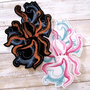 May include: Two embroidered iron-on patches featuring octopus designs. One octopus is orange and black with blue accents, the other is pink with teal accents.