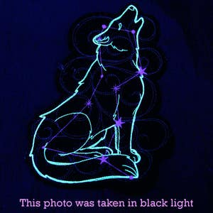 May include: A glowing blue wolf constellation embroidered patch. The wolf is howling at the moon and is surrounded by swirling lines. The patch is perfect for adding a touch of magic to any project.