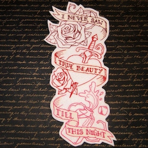 May include: Embroidered patch with a red heart, roses, and a dagger. The patch has three banners with the text "I Never Saw True Beauty Till This Night".