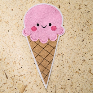 May include: A pink and brown embroidered ice cream cone patch with a smiling face.